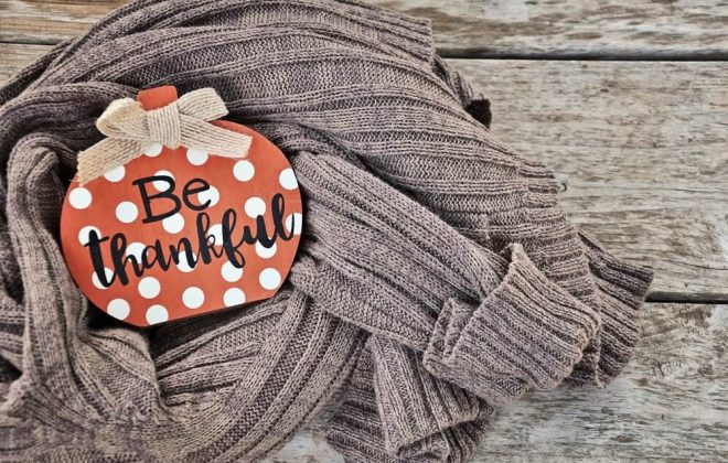 be thankful ornament on sweater with wood backdrop