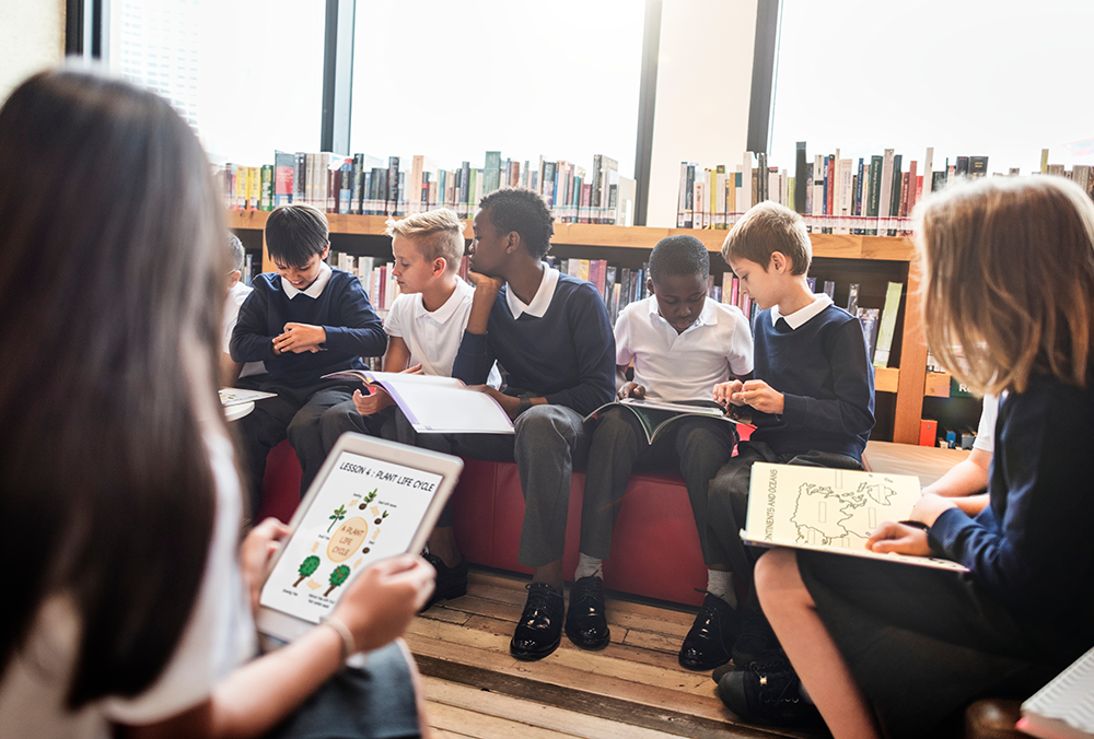 how sora supports diverse collections feature image: diverse mix of middle school students in uniform in the school library reading a mix of print books and books on devices