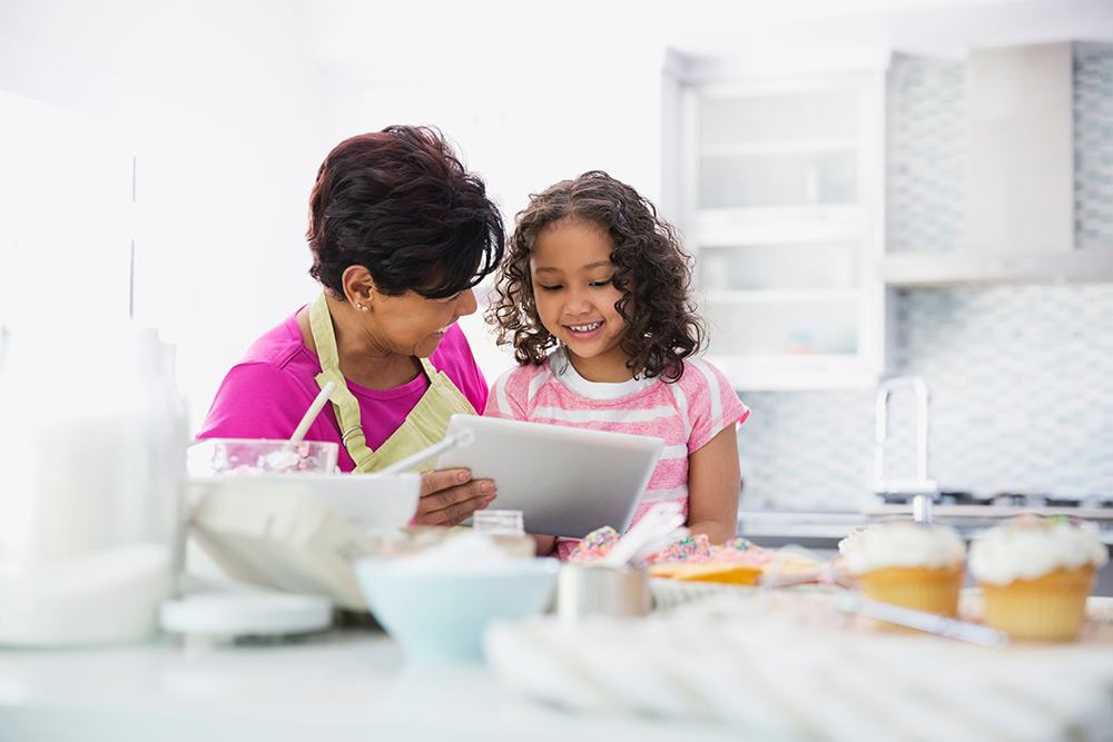 baking books: grandma and granddaughter consult tablet for recipes while baking