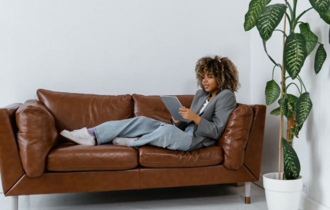 A reader sits comfortably on a brown leather couch enjoying an ebook she found through a guide in the Libby app