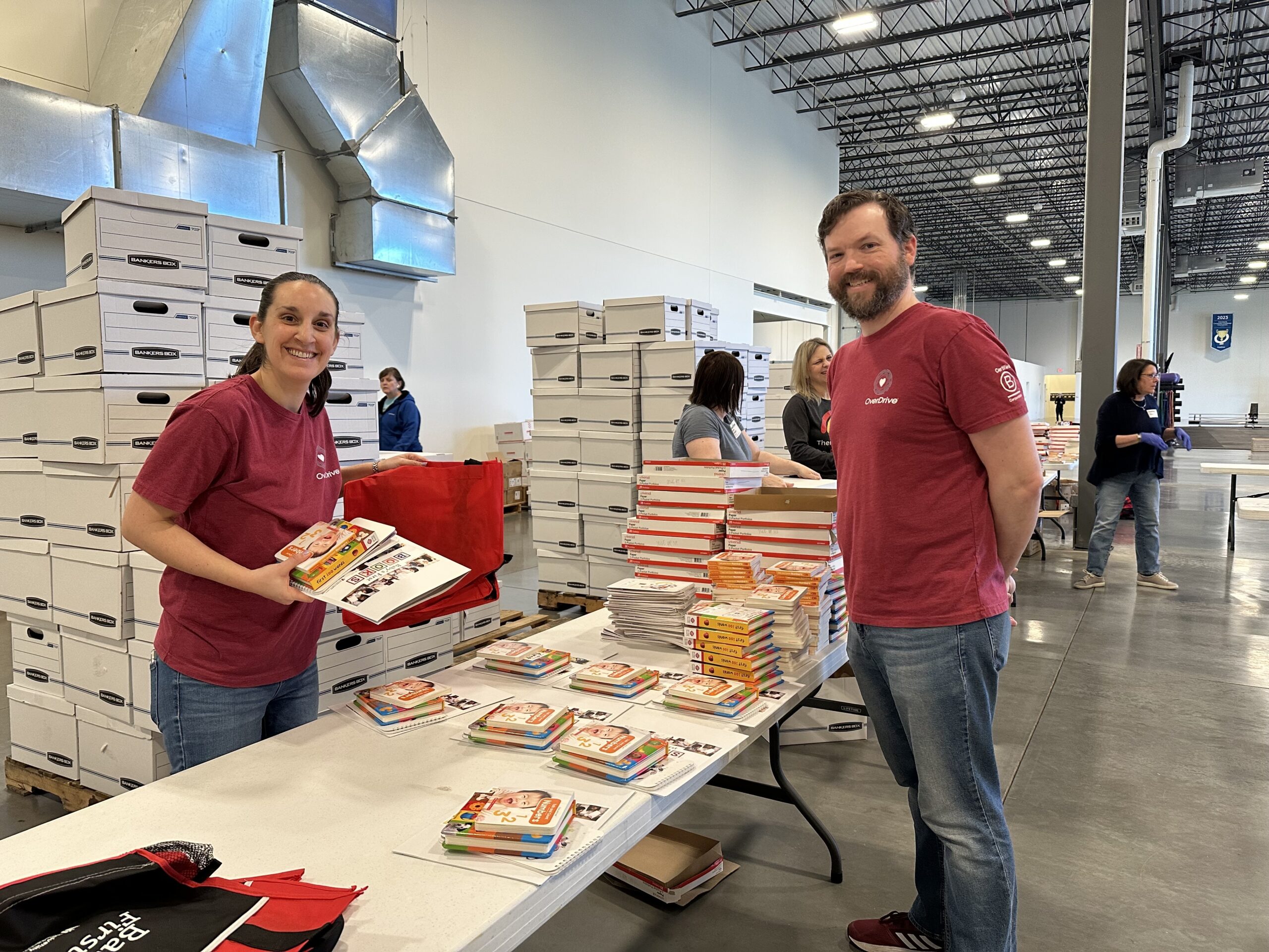 Employees smiling as they put bundles of book together for a volunteer event