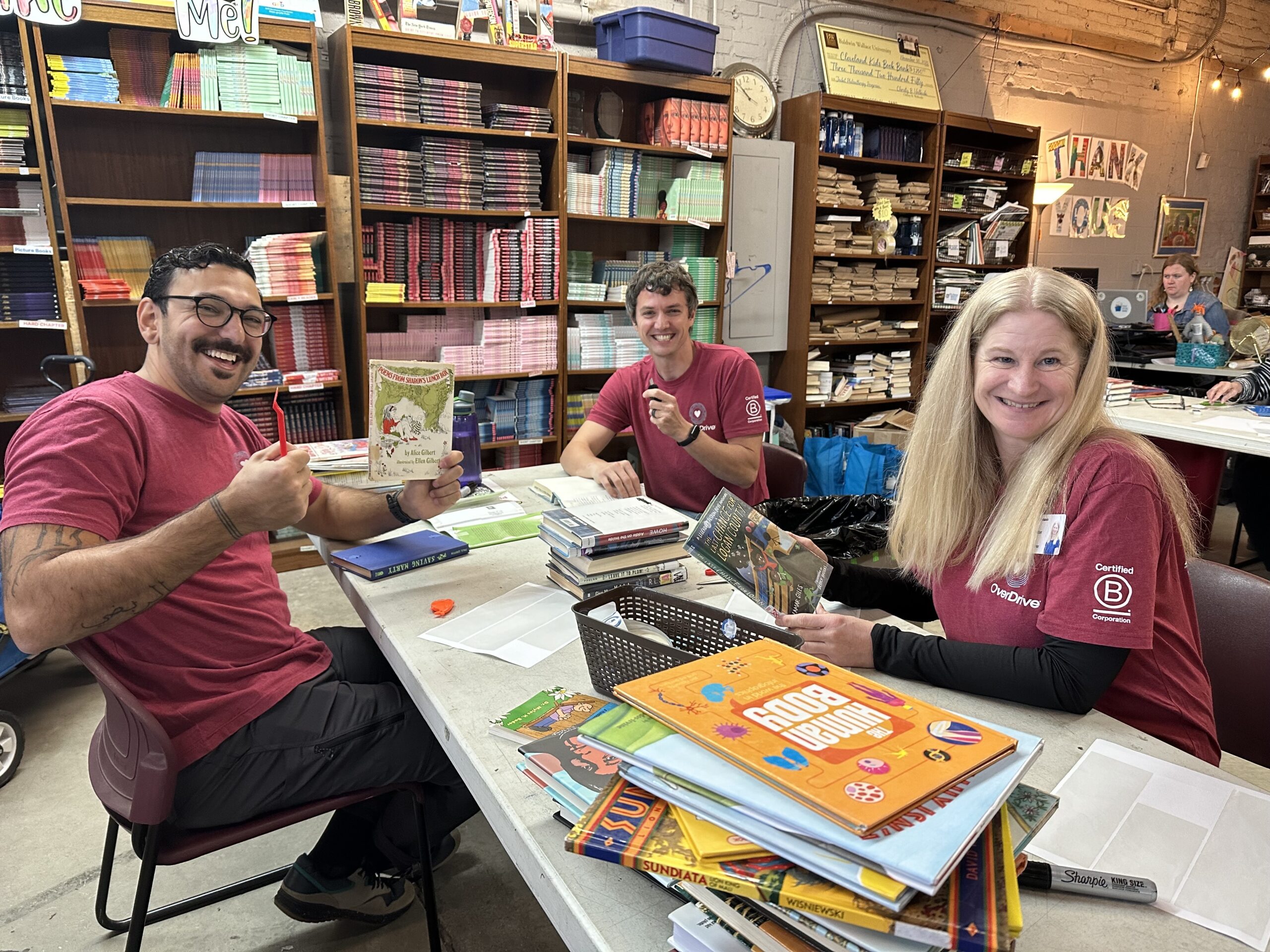 Employees smiling as they sort books at a volunteer event