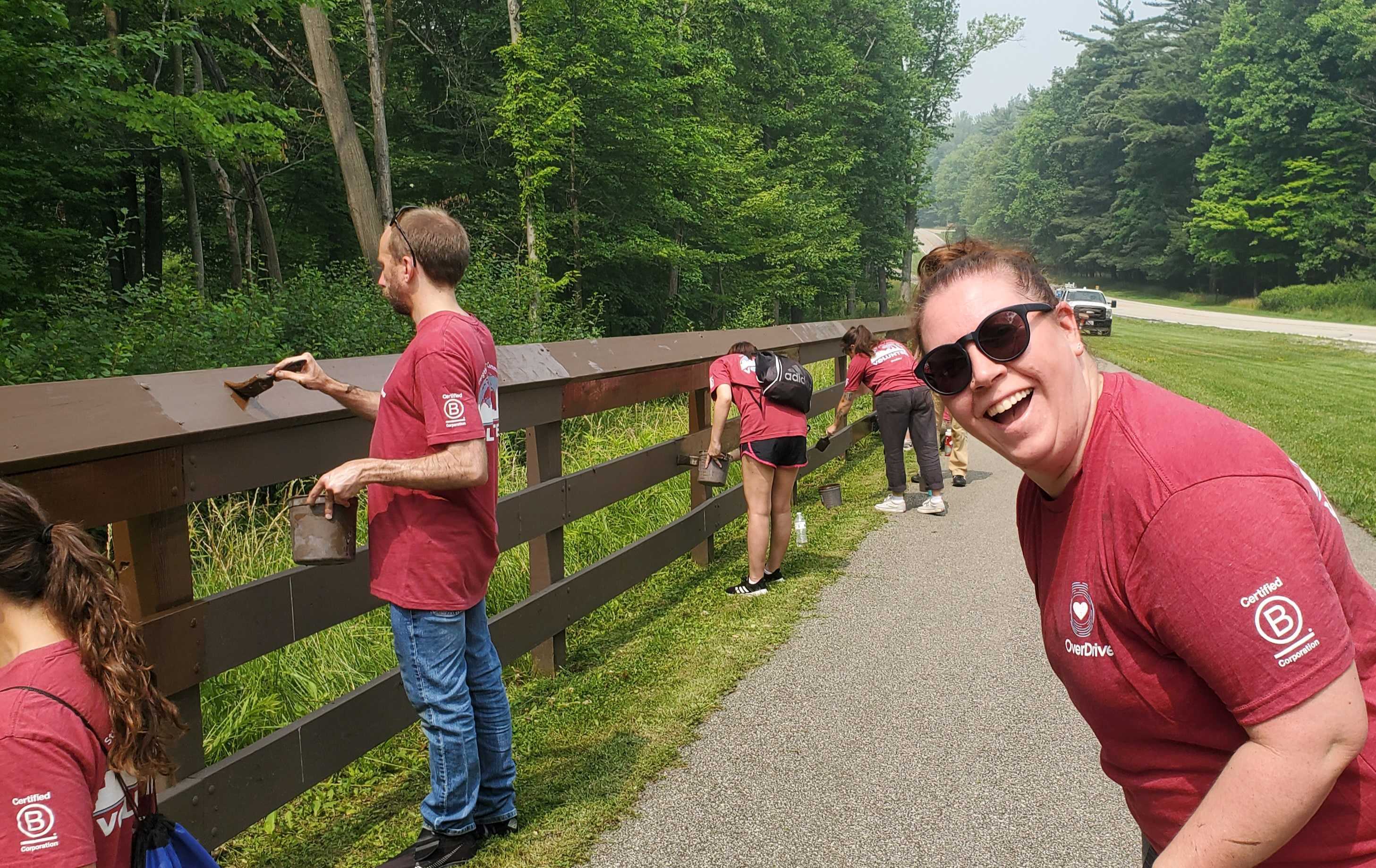 Employees painting a fence at a volunteer event